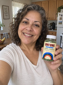 Woman in a white t-shirt holding UNFUNK, in her kitchen
