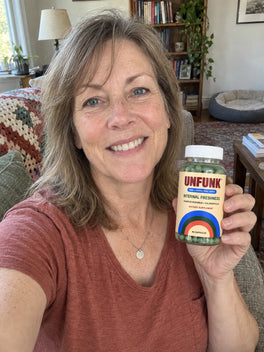 Woman in a rust top holding UNFUNK, in her living room