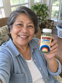 Woman in a denim shirt holding UNFUNK, in her sunroom